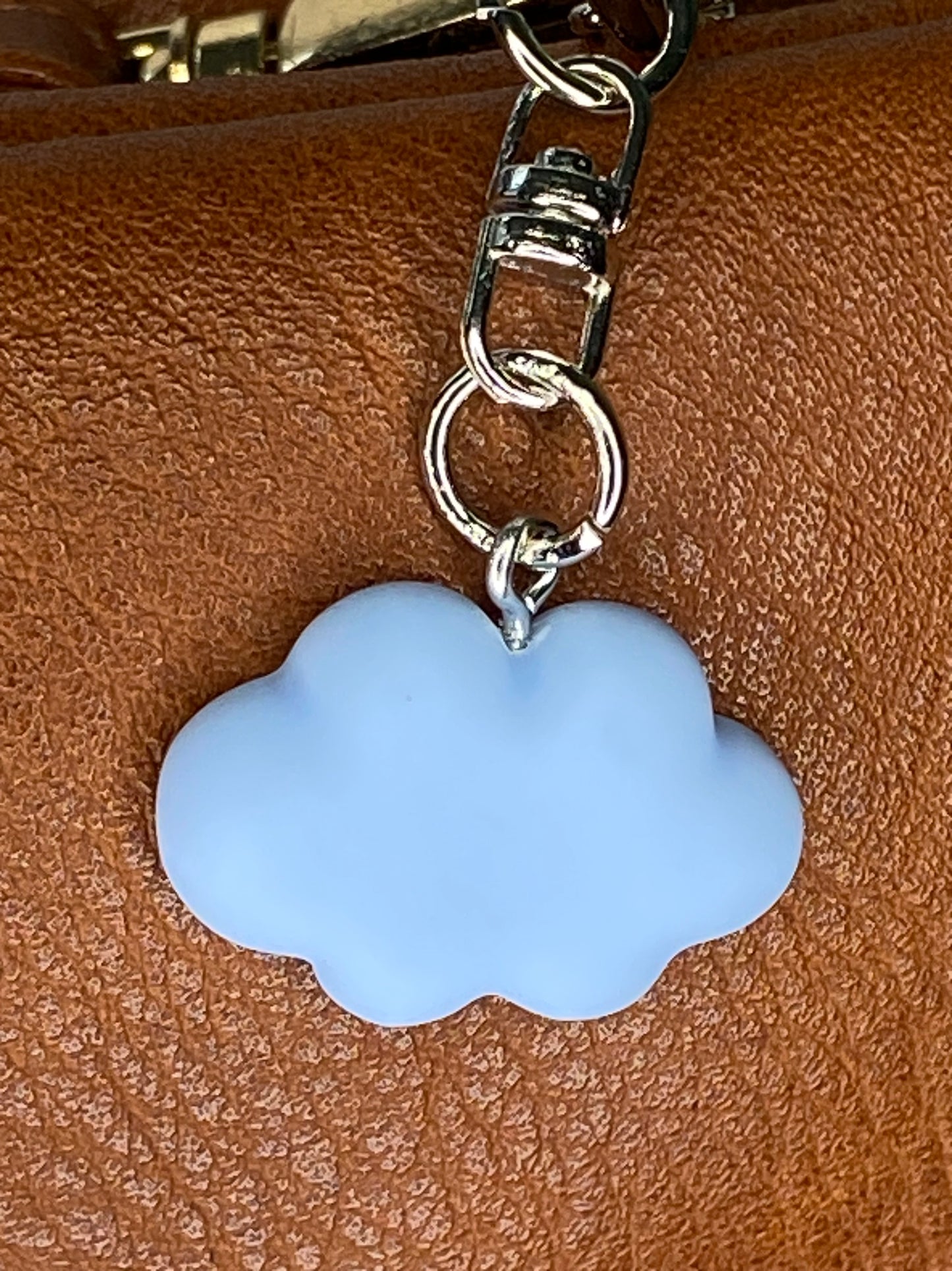 Blue cloud-shaped keychain attached to a brown leather surface
