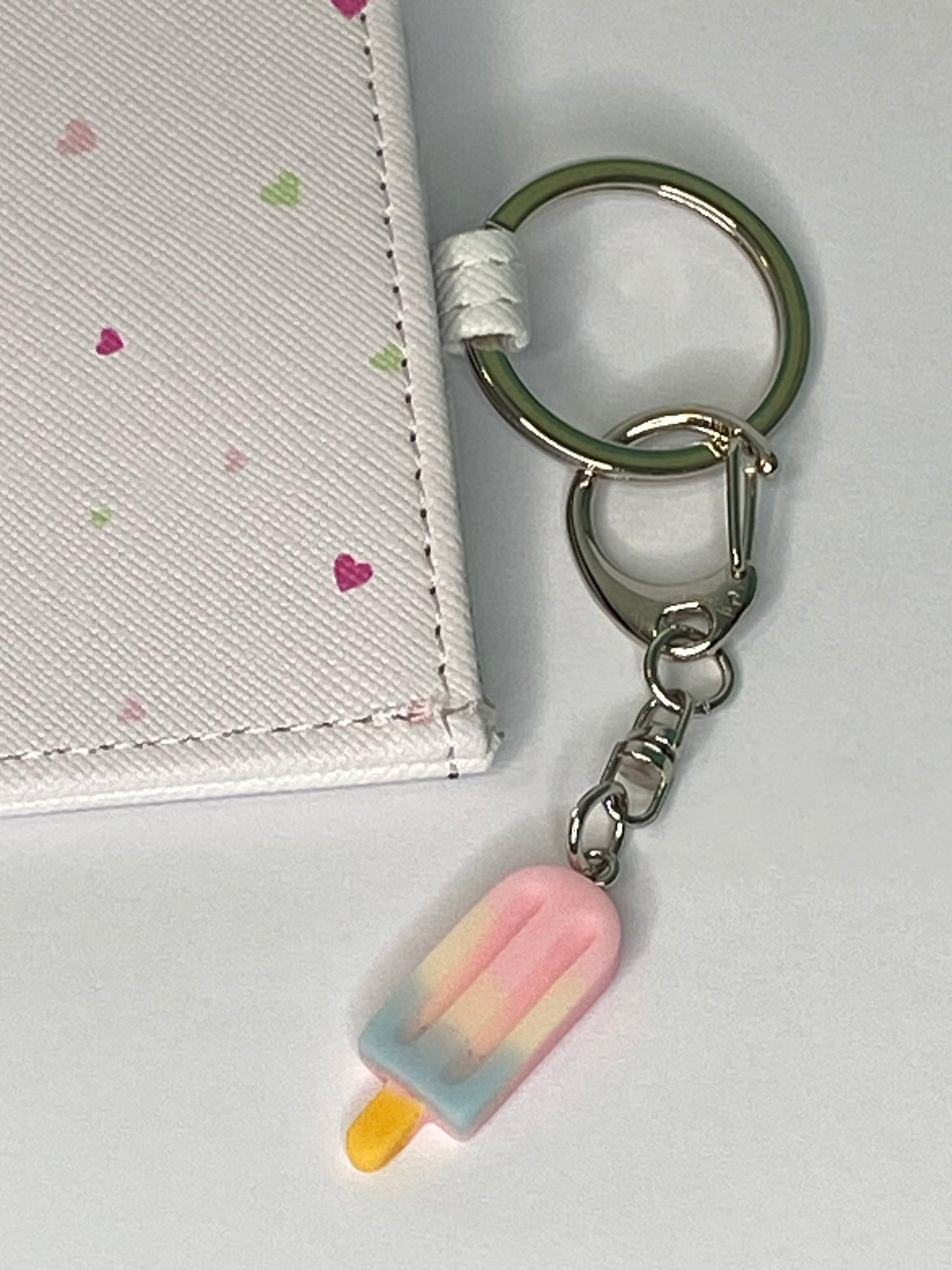 Keychain with a pink popsicle charm attached to a white surface