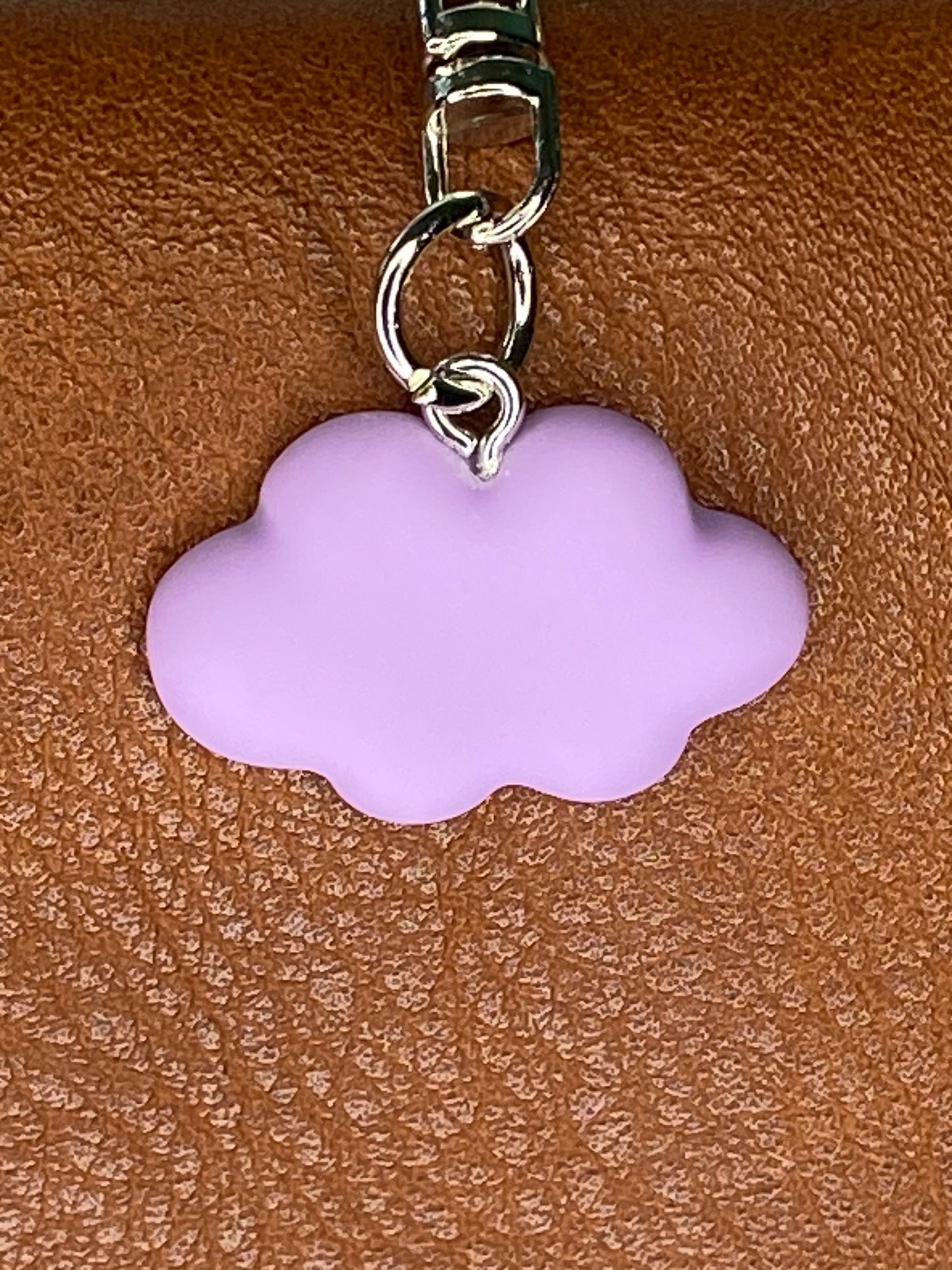 Purple cloud-shaped charm on a brown leather surface