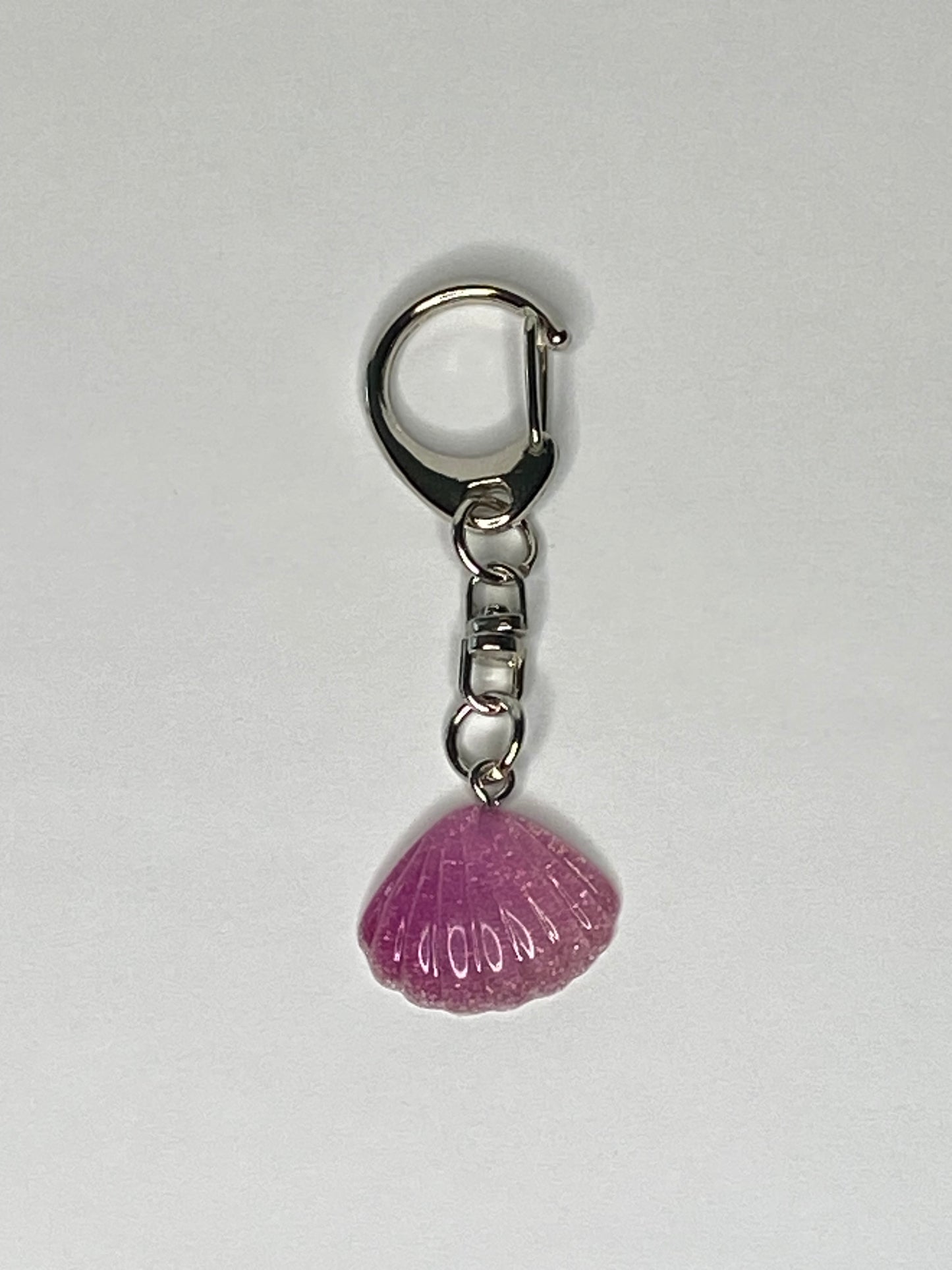 Keychain with a violet shell-shaped charm on a light gray background