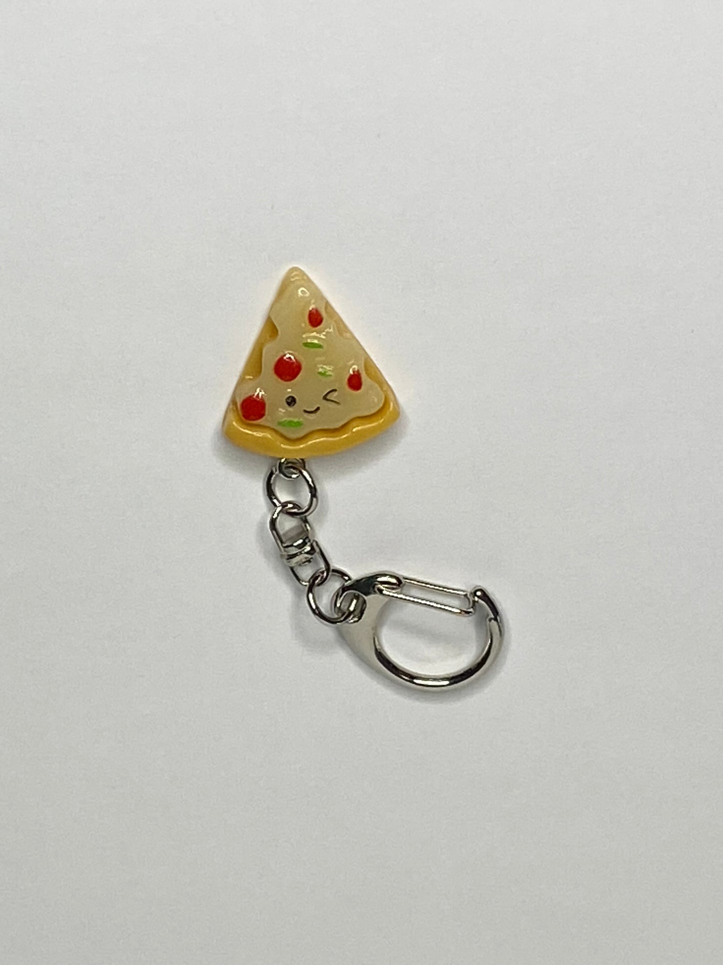 Keychain shaped like a pizza slice with a face on a light gray background