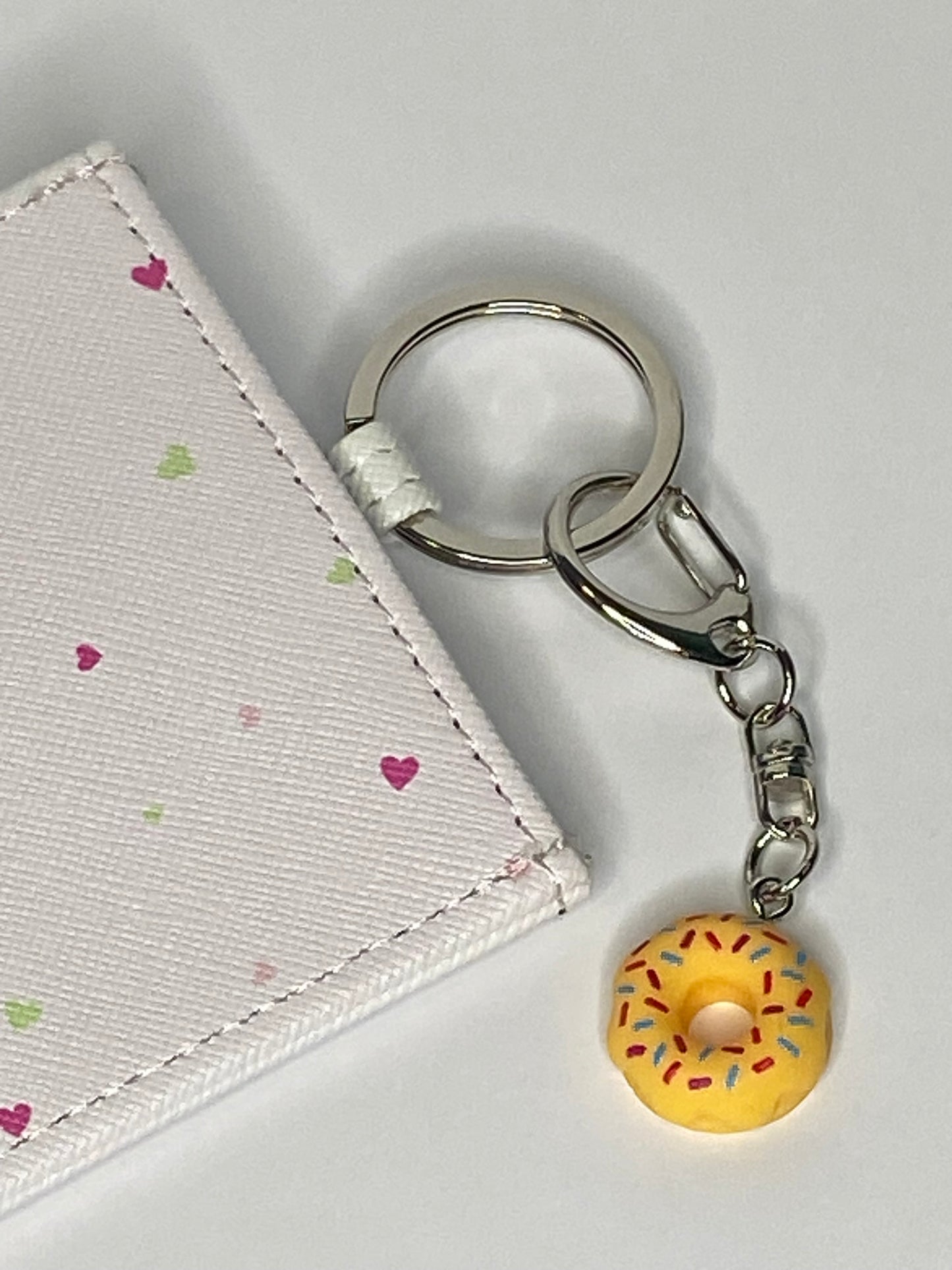 Keychain with a donut charm attached to a cardholder on a light gray background