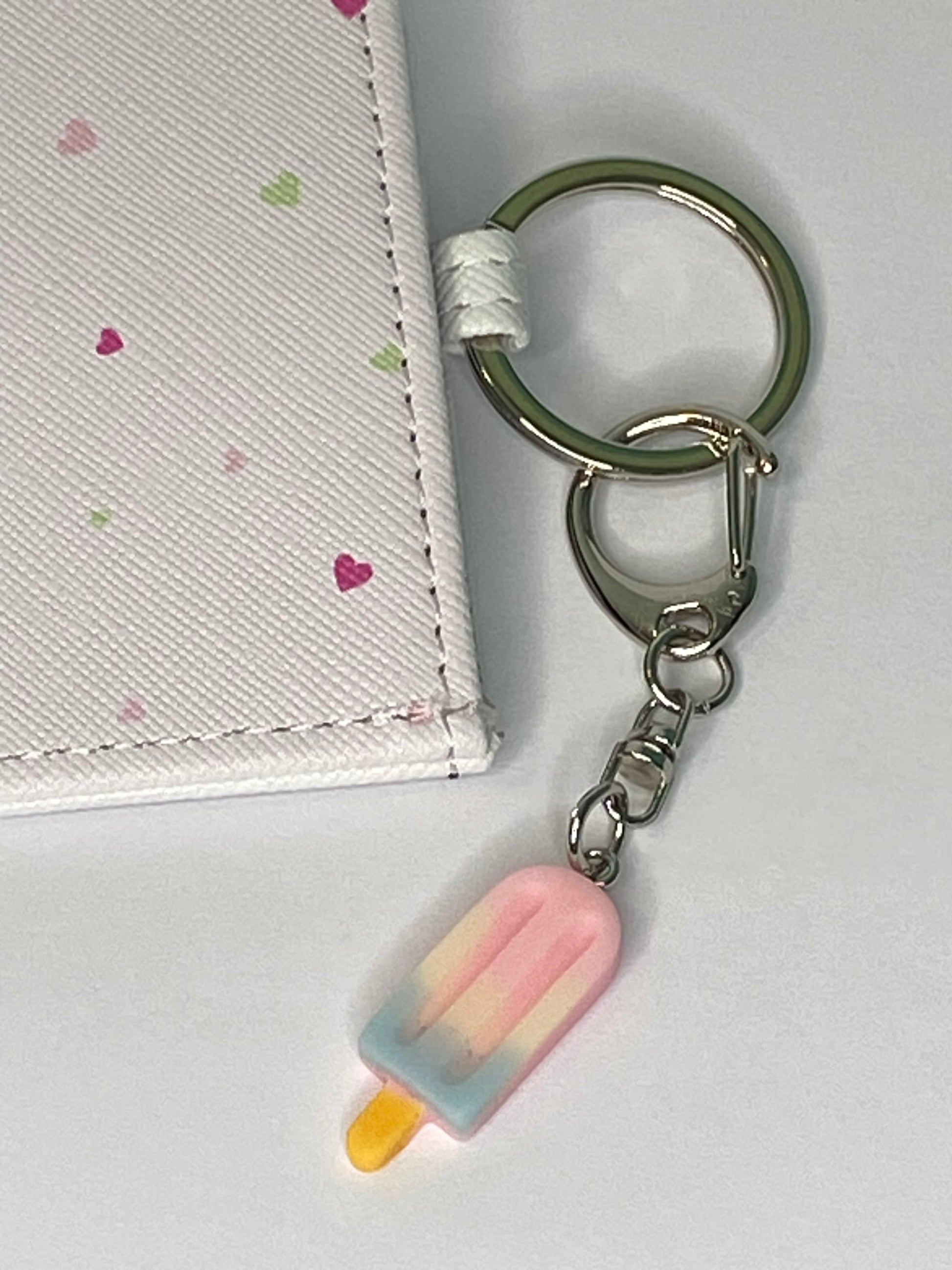 Keychain with a pink popsicle charm attached to a white surface
