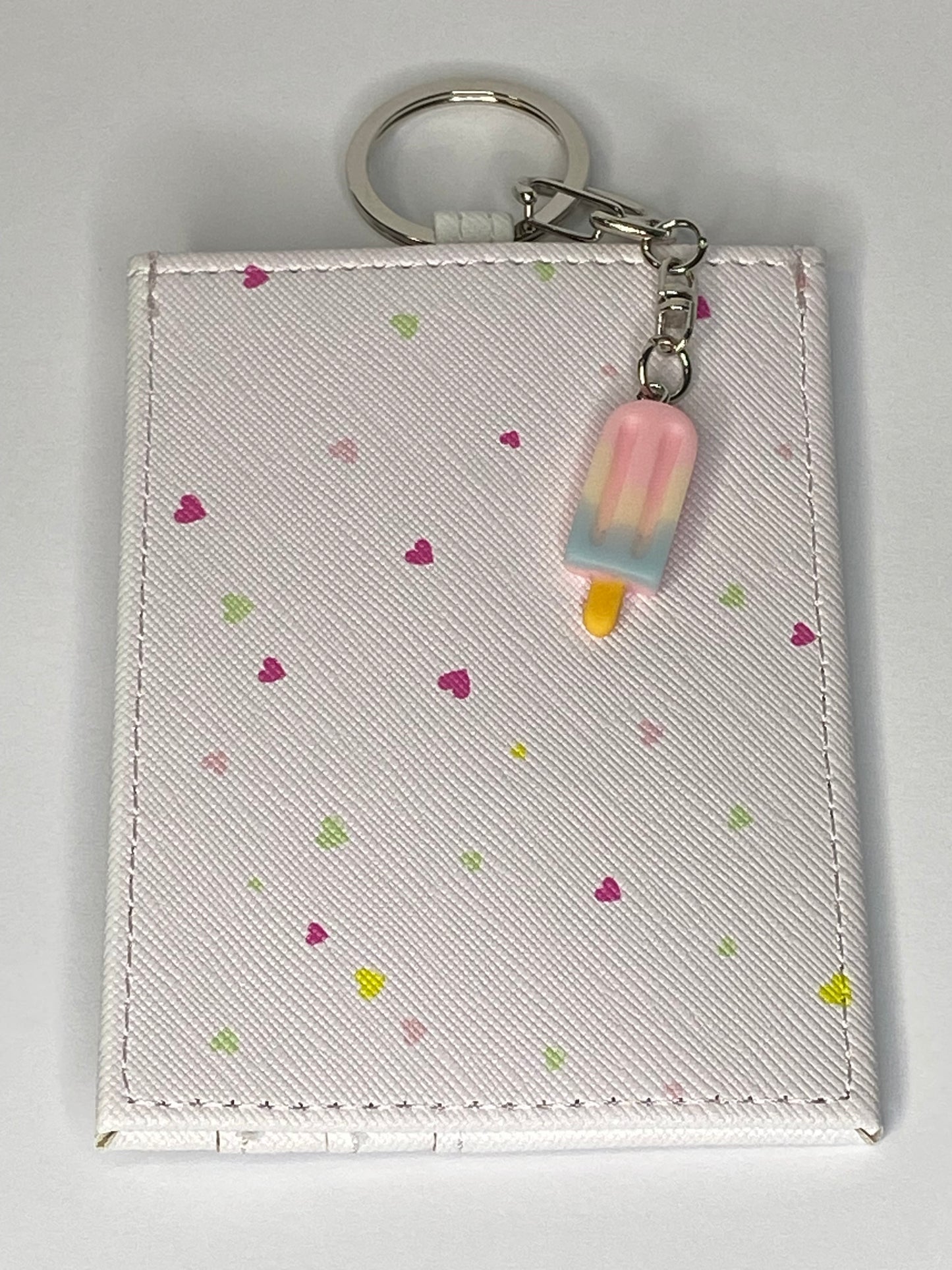 Small pouch with keychain and pink popsicle charm on a light gray background