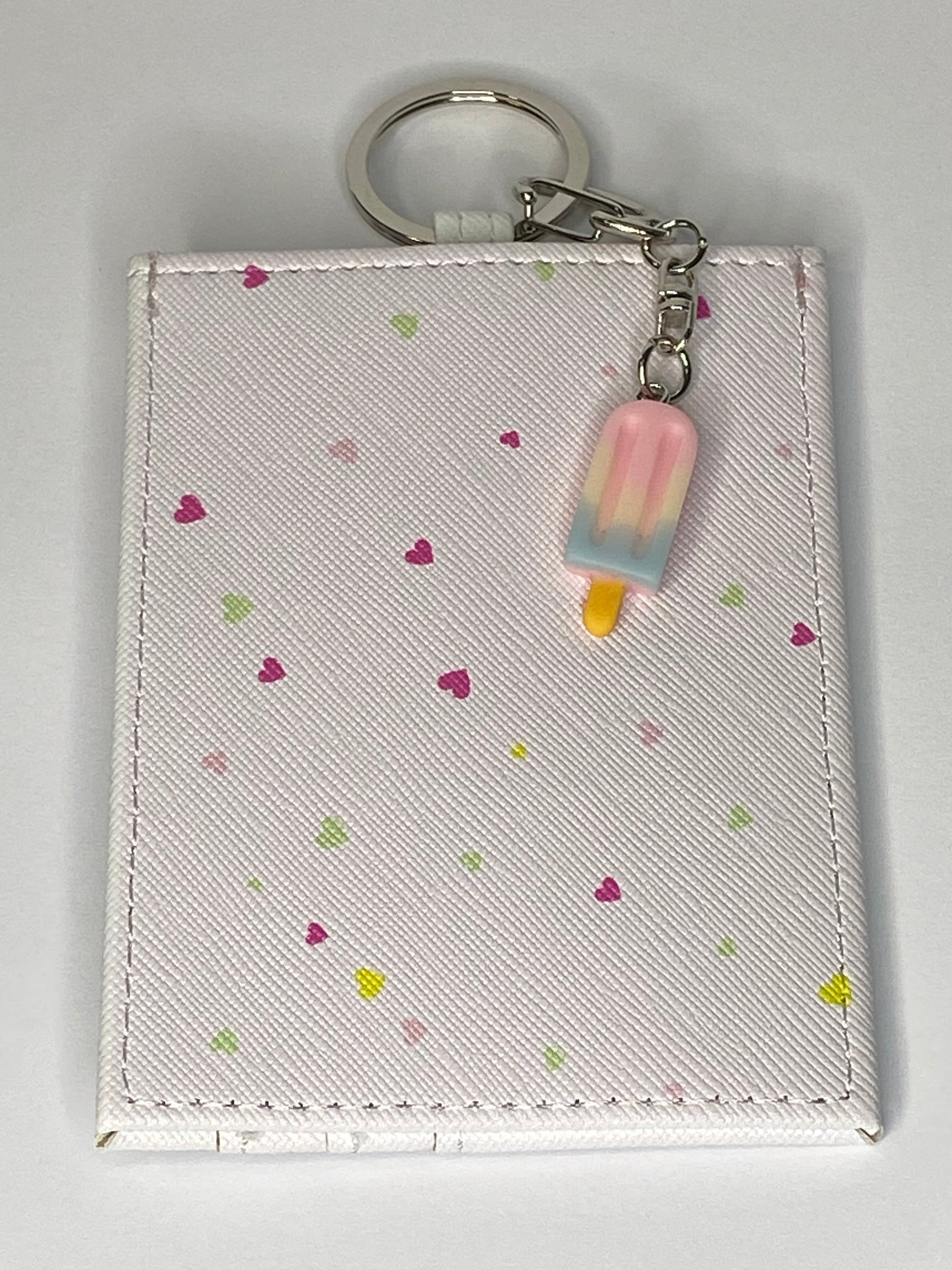Small pouch with keychain and pink popsicle charm on a light gray background