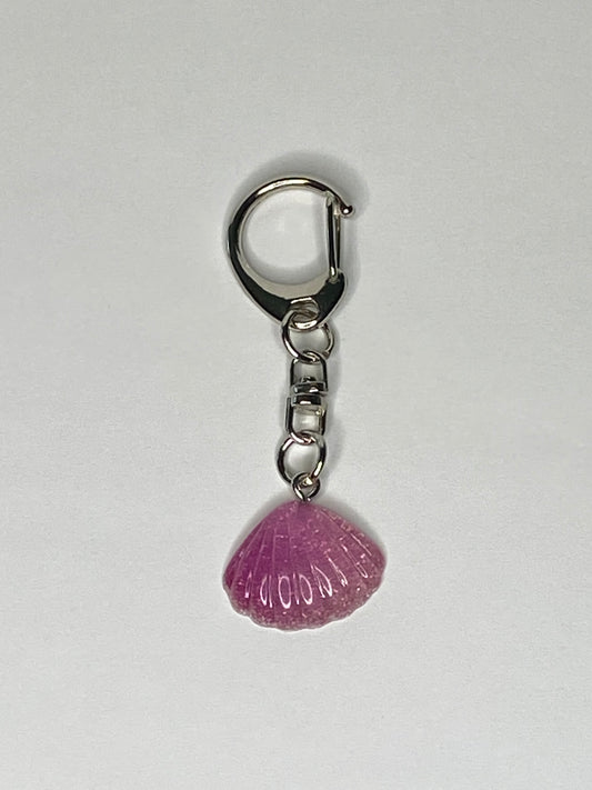 Keychain with a violet shell-shaped charm on a light gray background