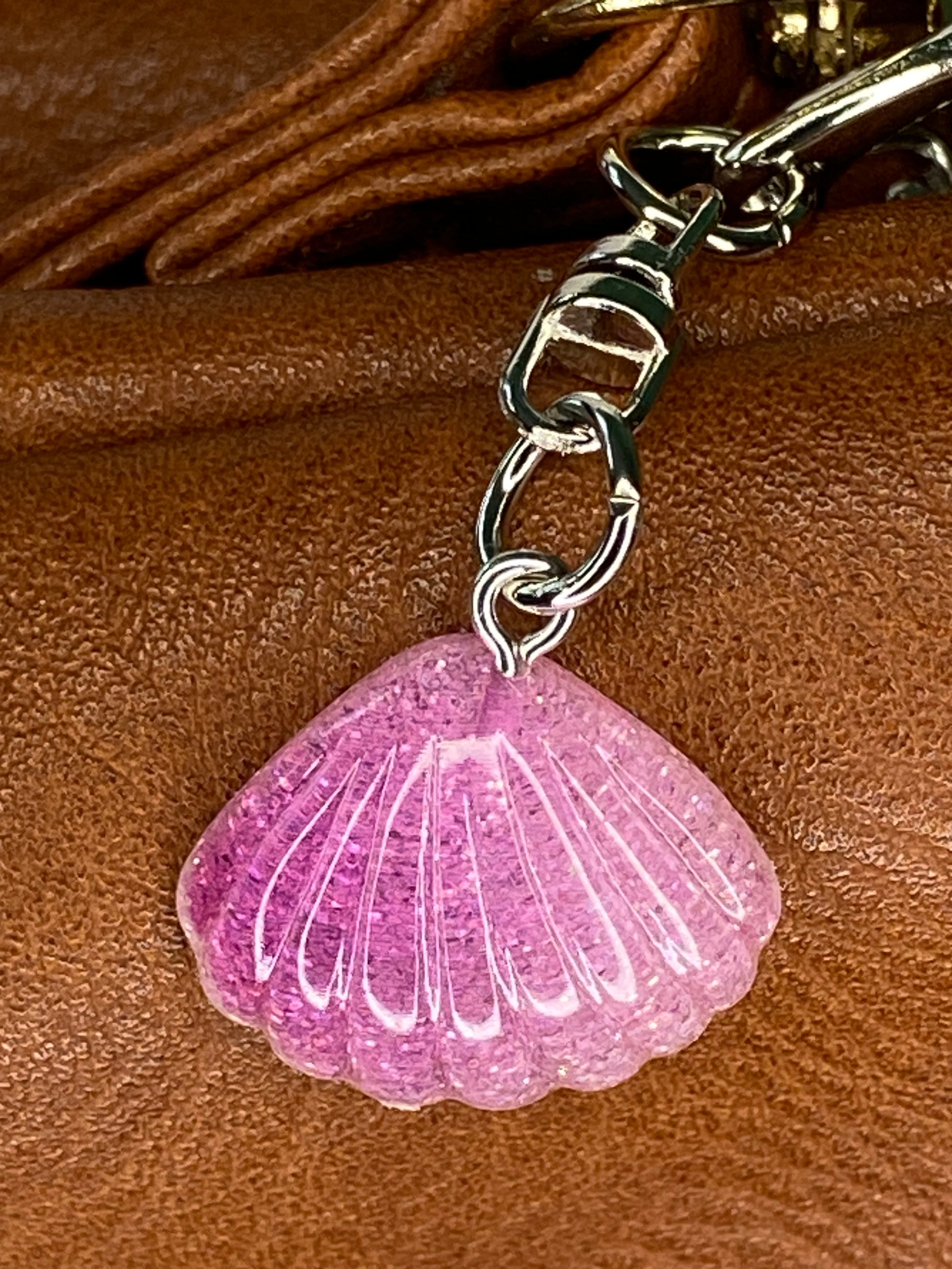 violet shell keychain attached to a brown leather bag